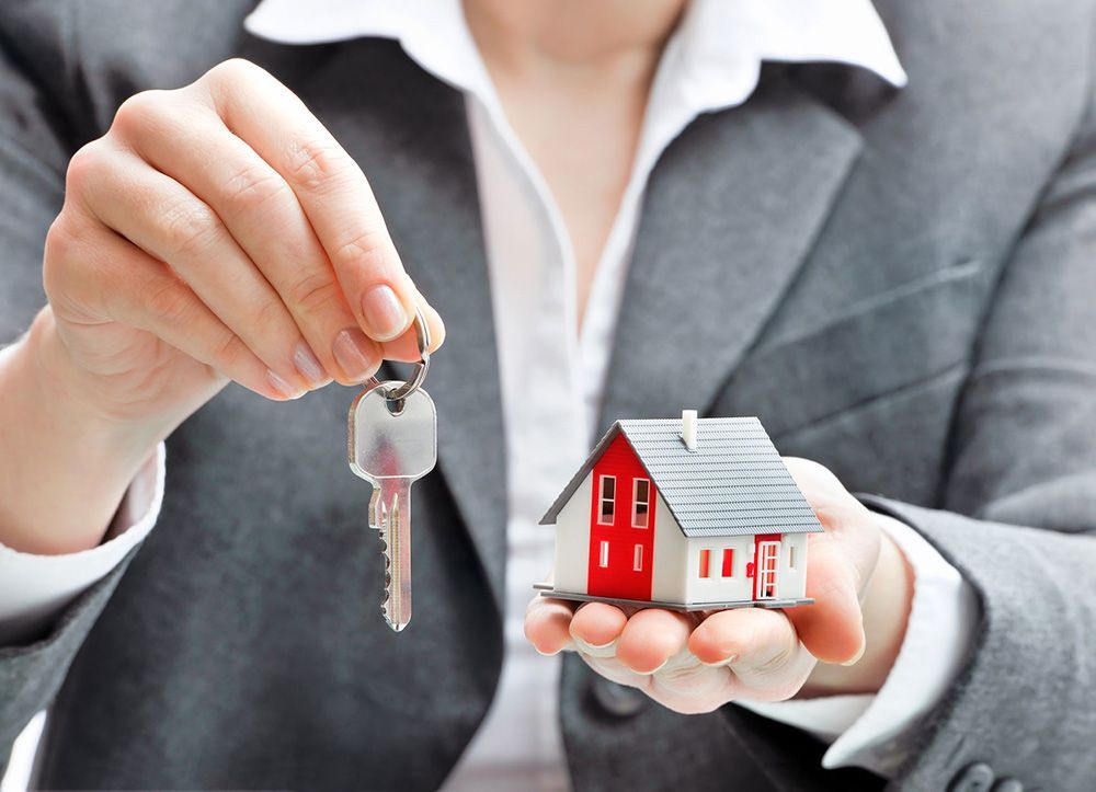 A woman is holding a model house and keys