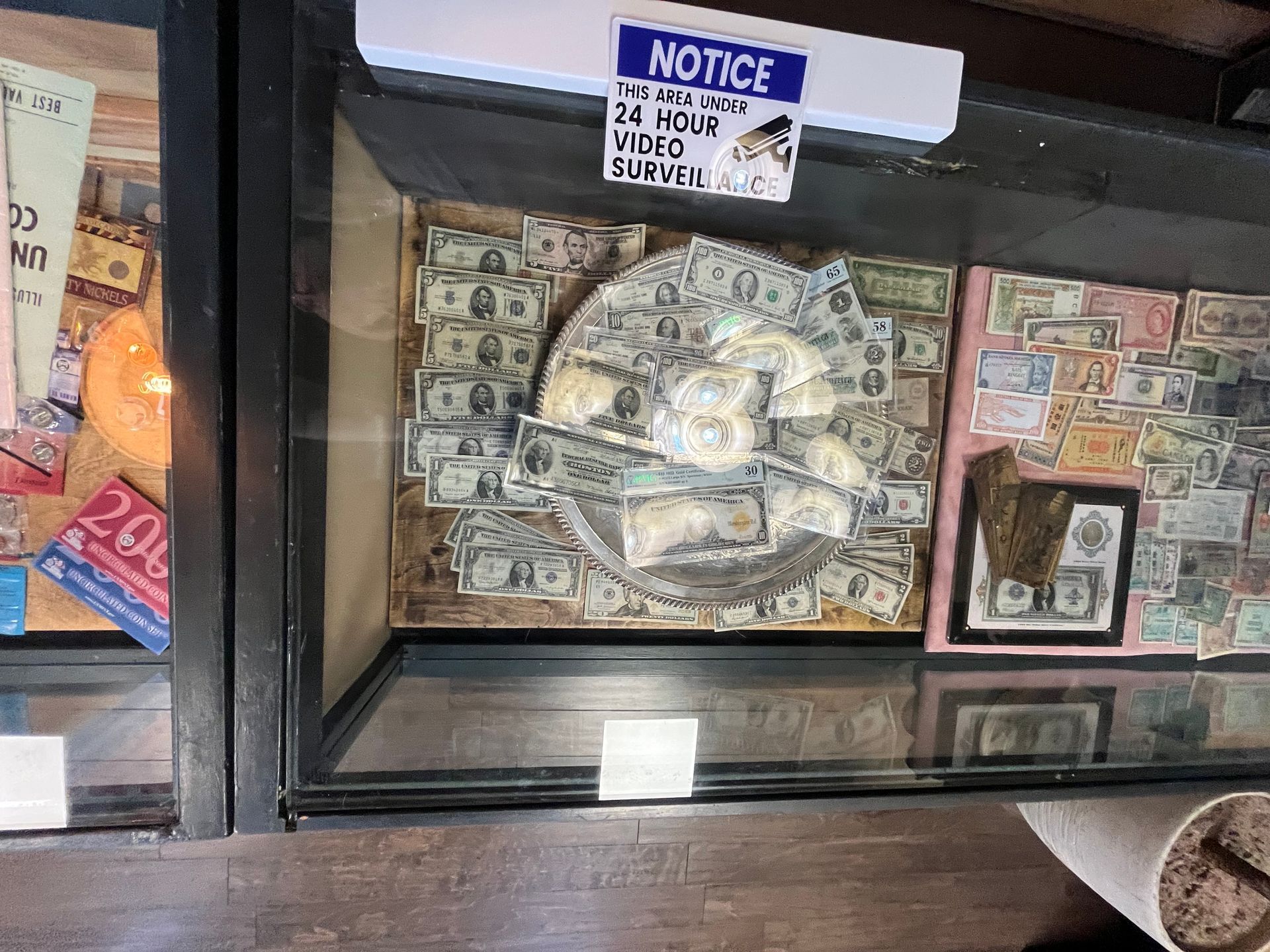 A glass display case containing many paper bills mounted on the back wall and a circular collection of bills inside.
