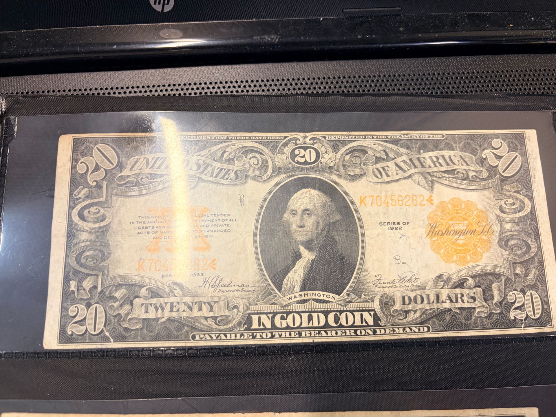A vintage twenty-dollar gold certificate banknote featuring George Washington, encased in a black protective sleeve.
