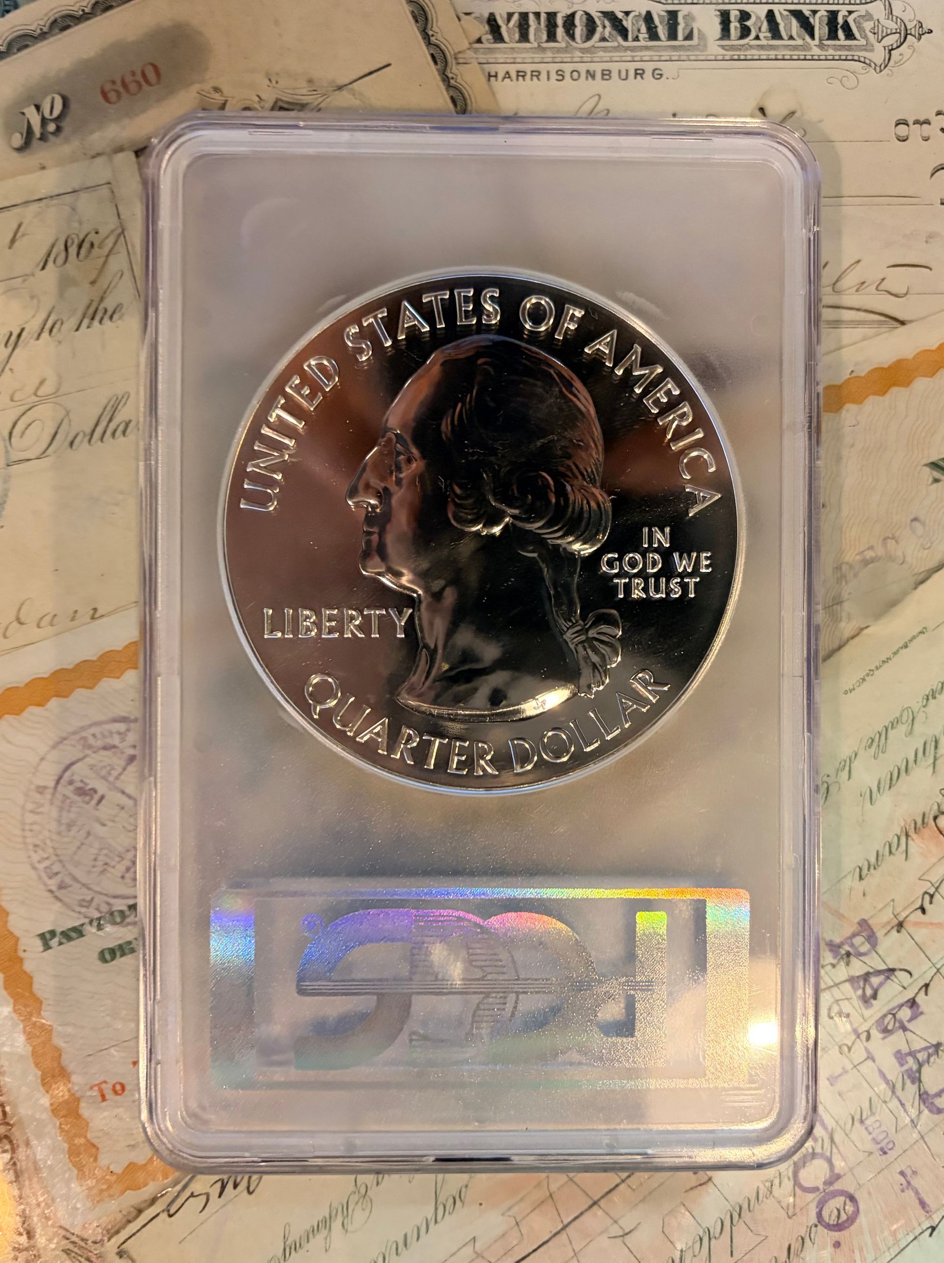 A proof-finish US quarter coin encapsulated in a protective plastic slab with a holographic sticker at the bottom.