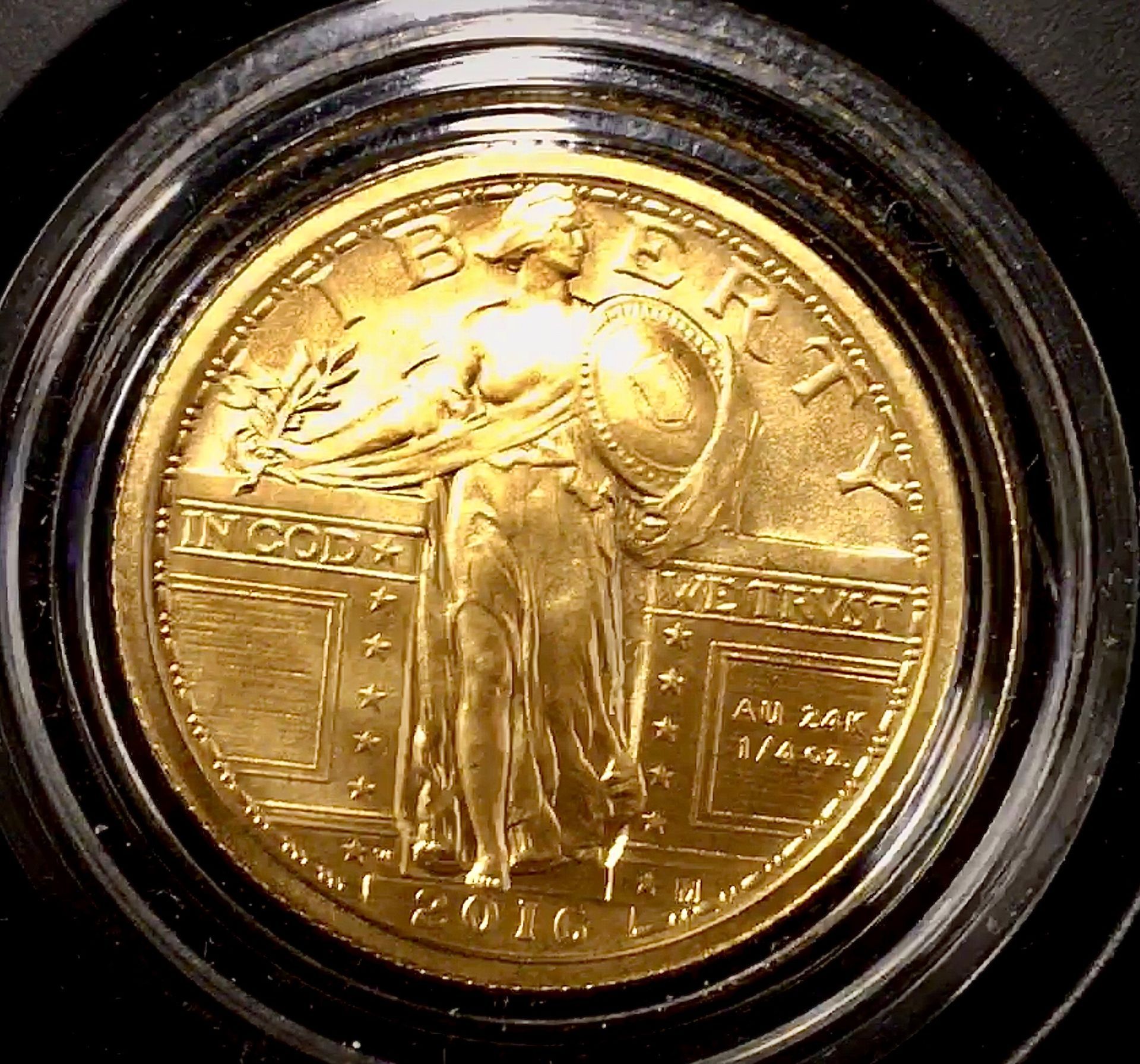 A 2016 gold Standing Liberty quarter centennial coin in a protective case, showing Liberty holding a shield and branch.