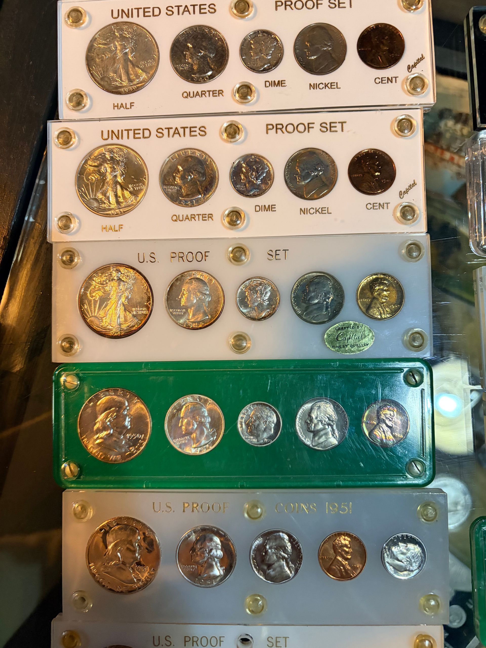 A vertical stack of six plastic holders containing U.S. proof coin sets, featuring various denominations of silver coins.