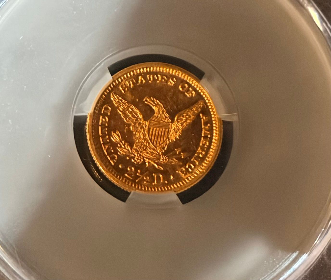 A United States $2.50 gold coin featuring an eagle, encased in a protective plastic holder.
