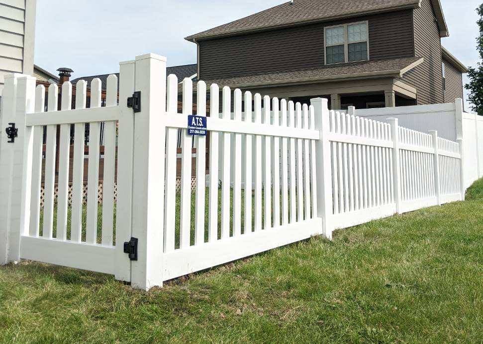 A white picket fence is in front of a house.