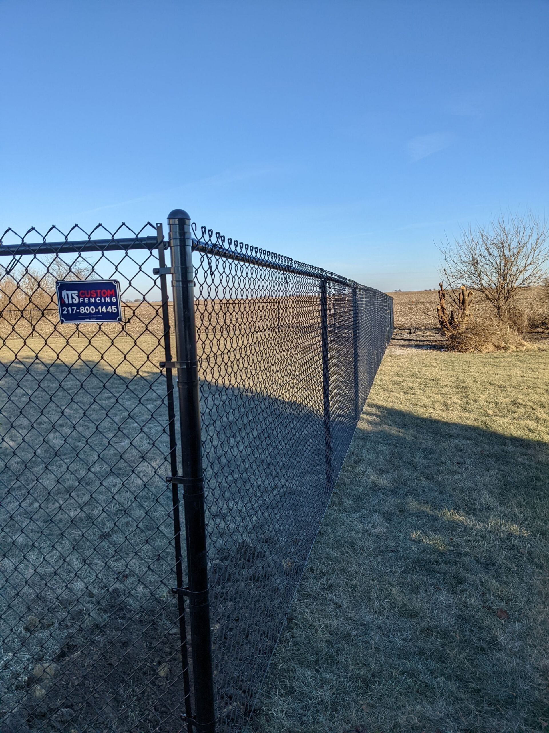 A chain link fence is surrounding a grassy field.