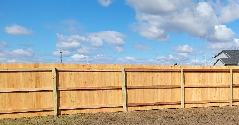 A wooden fence is sitting in the middle of a grassy field.