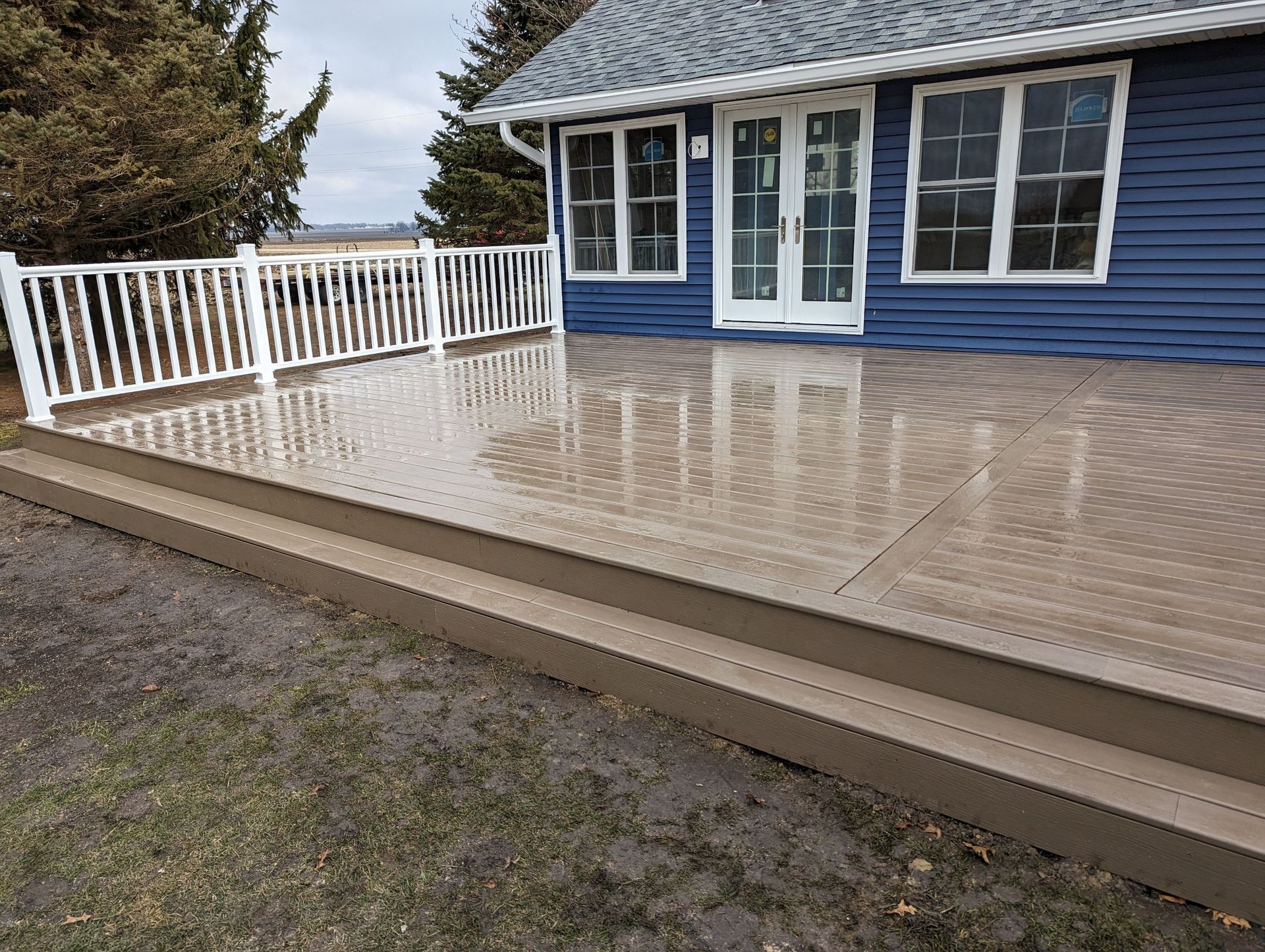 A blue house with a large deck in front of it.