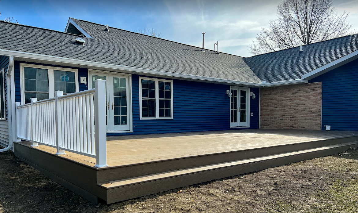 A blue house with a large deck in front of it.