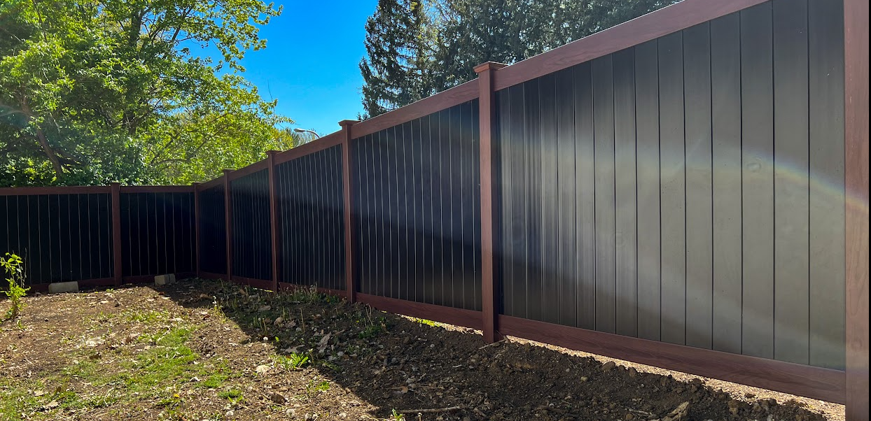 A black fence is surrounded by trees in a backyard.
