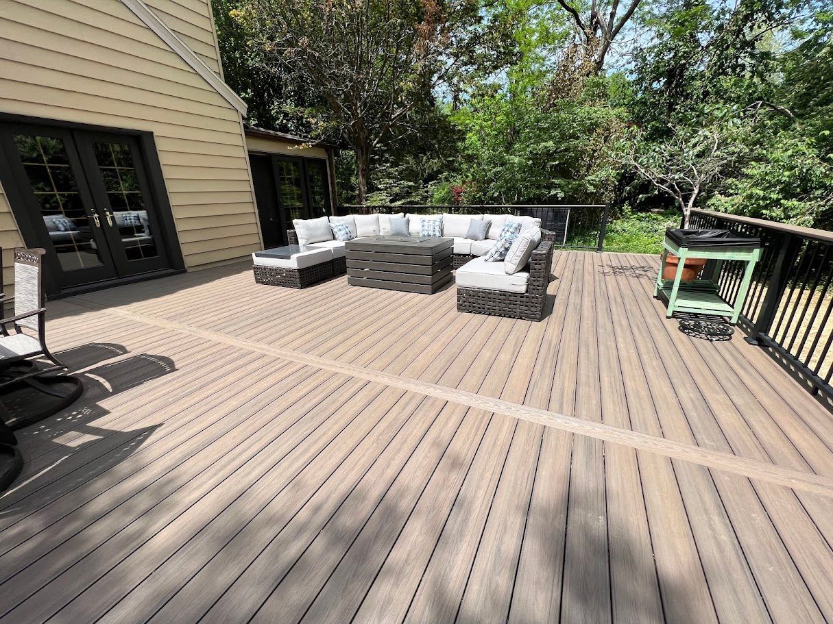 A large wooden deck with a couch and chairs on it.