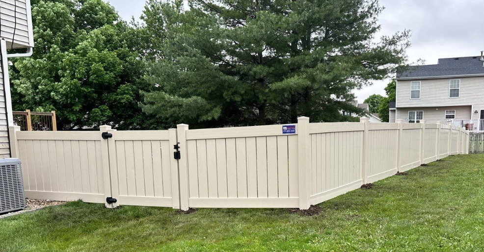 A white fence with a gate in the backyard of a house.