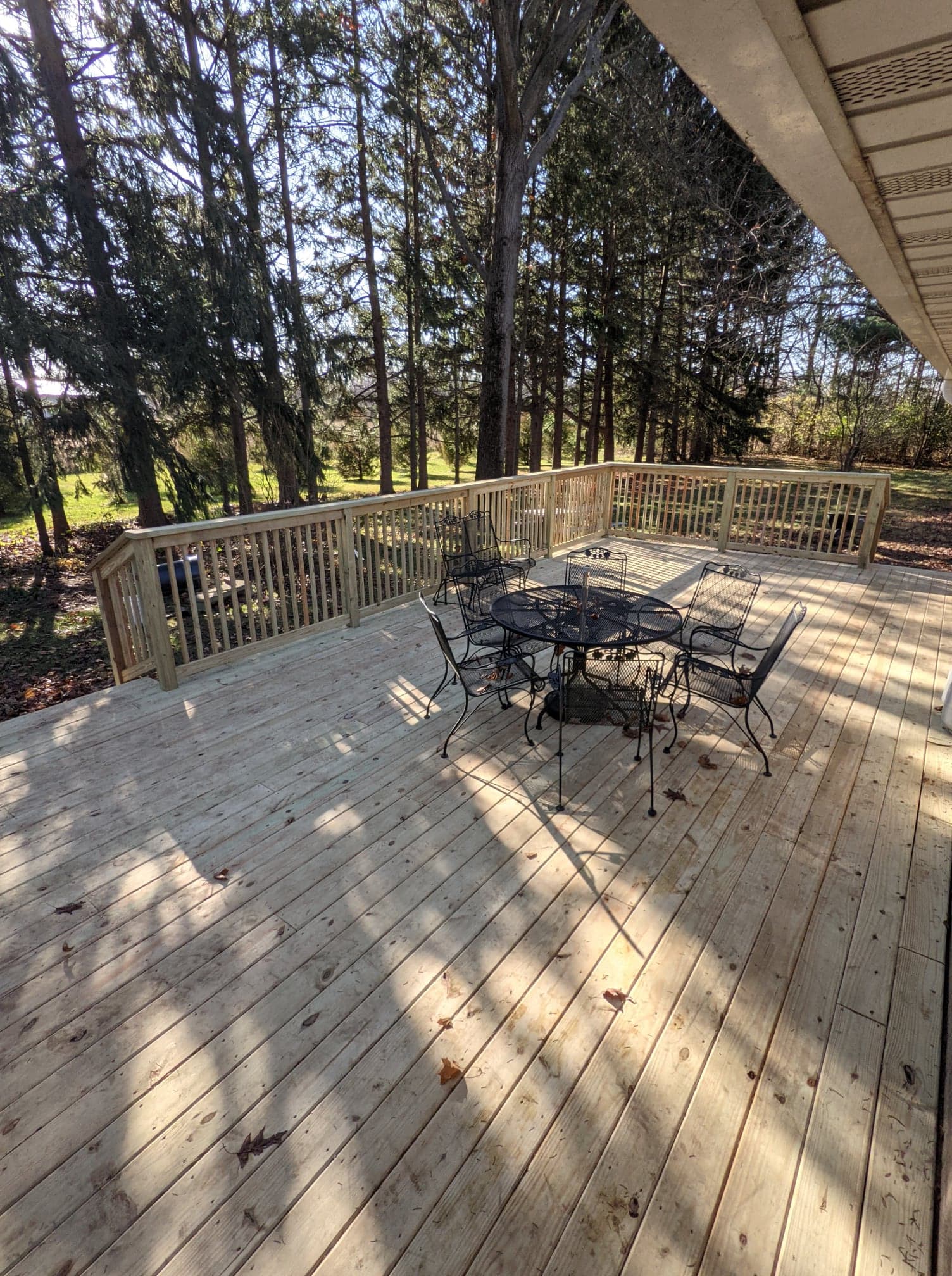 A wooden deck with a table and chairs on it surrounded by trees.