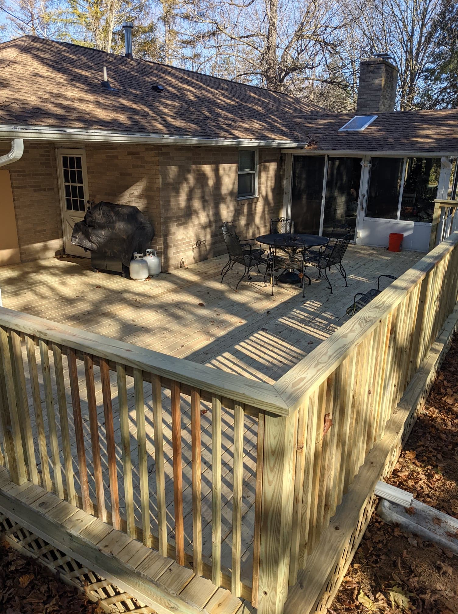A large wooden deck is sitting in front of a brick house.