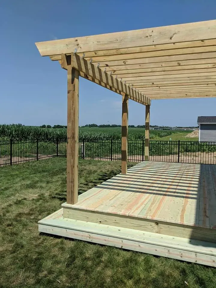 A wooden pergola is sitting on top of a wooden deck.