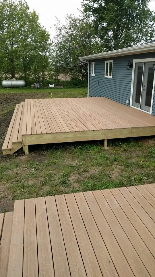 A wooden deck is sitting in front of a house.