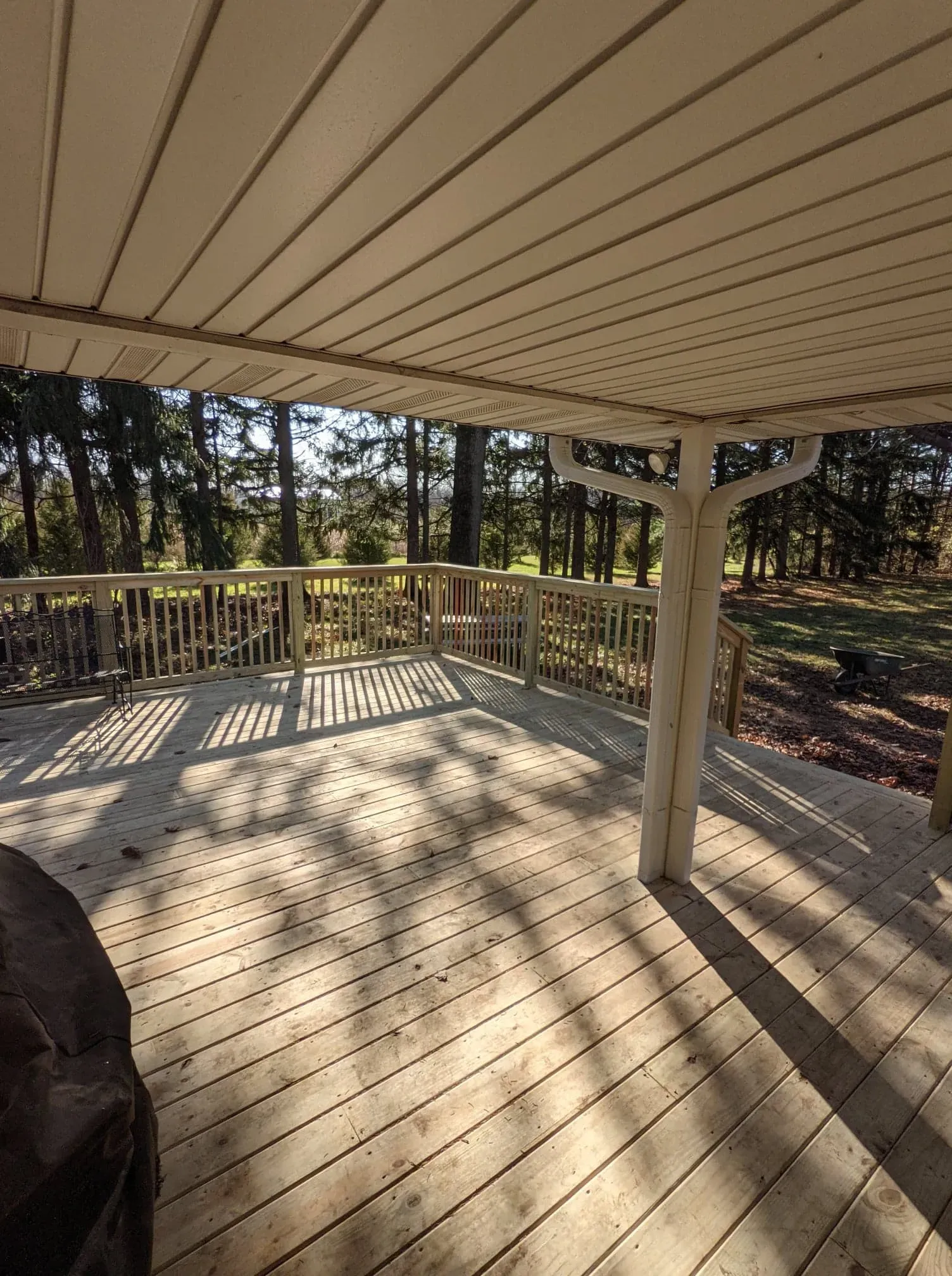 A wooden deck with a white railing and trees in the background.