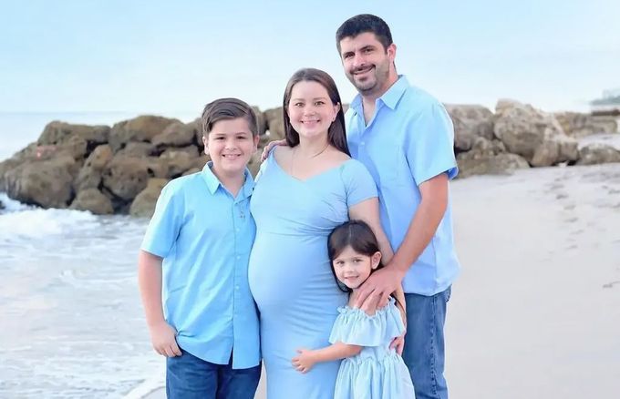 A family is posing for a picture on the beach.