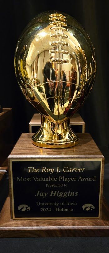 A gold football trophy is sitting on top of a wooden pedestal.