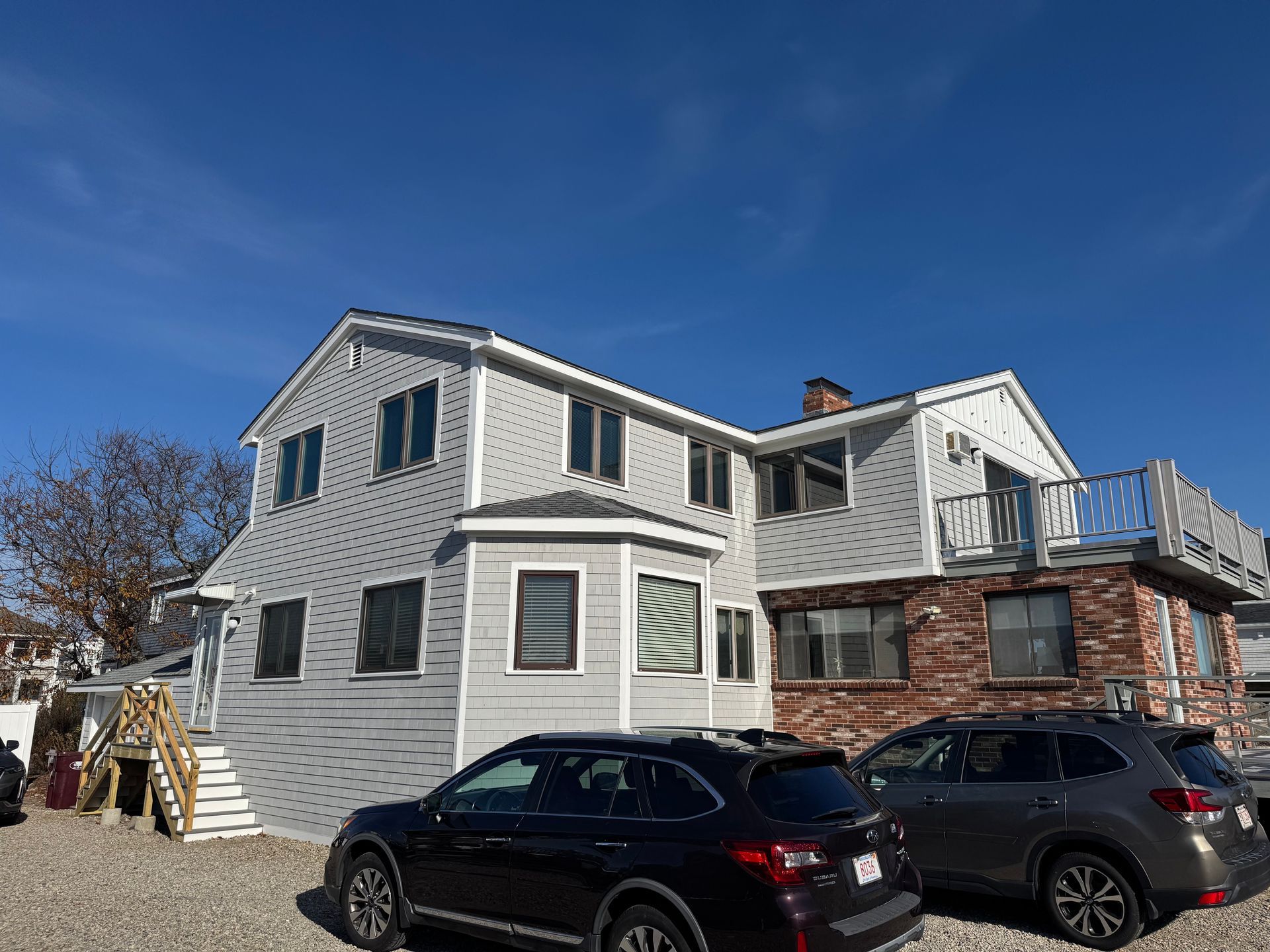 Two cars are parked in front of a large house.