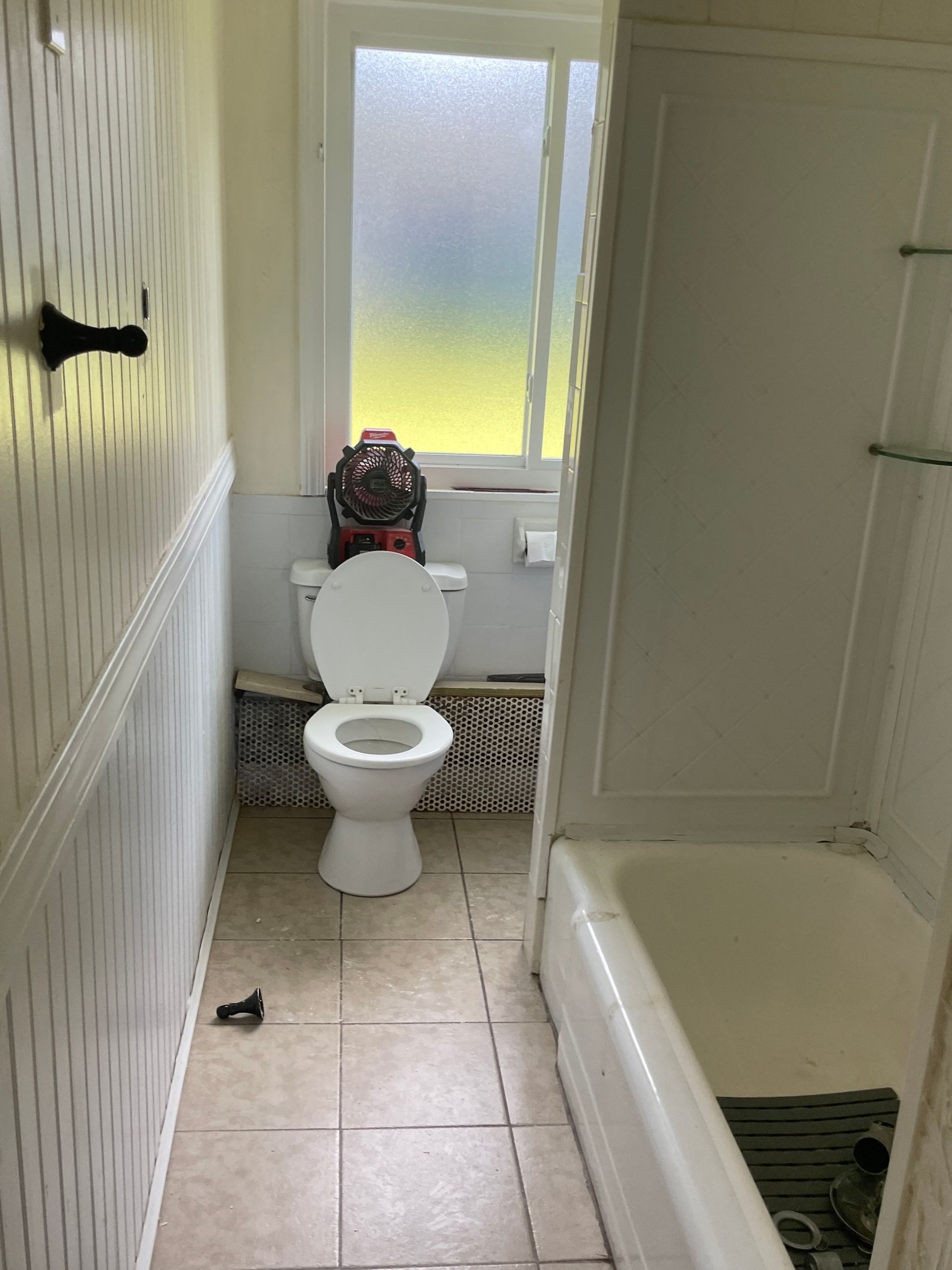 A bathroom with a toilet , tub and window.