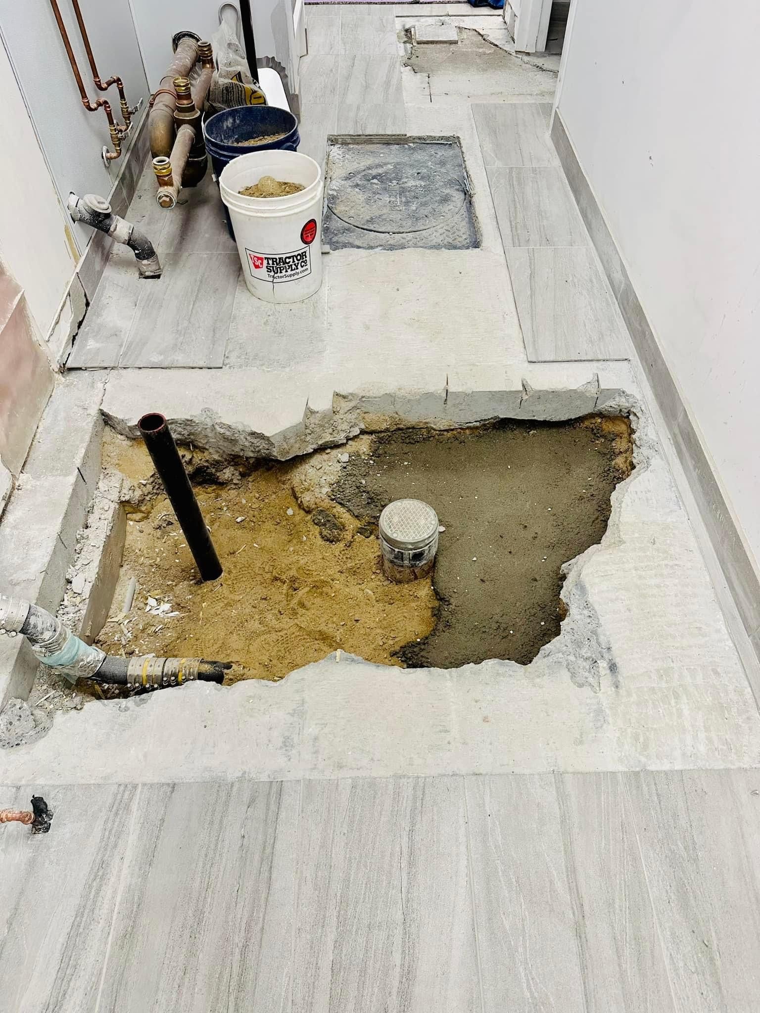 a hole in the floor of a building with a bucket of sand in it