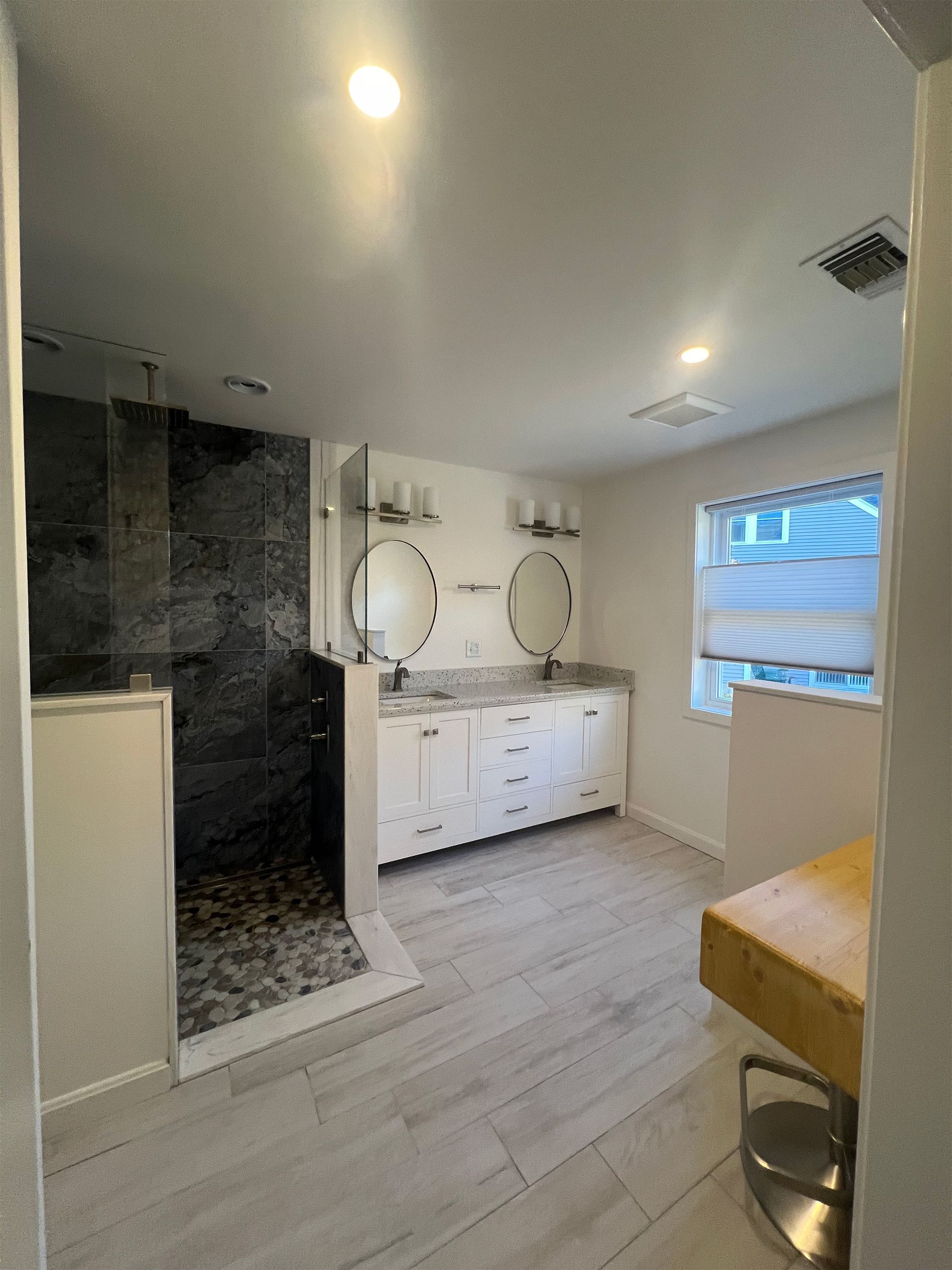 A bathroom with two sinks and a walk in shower.
