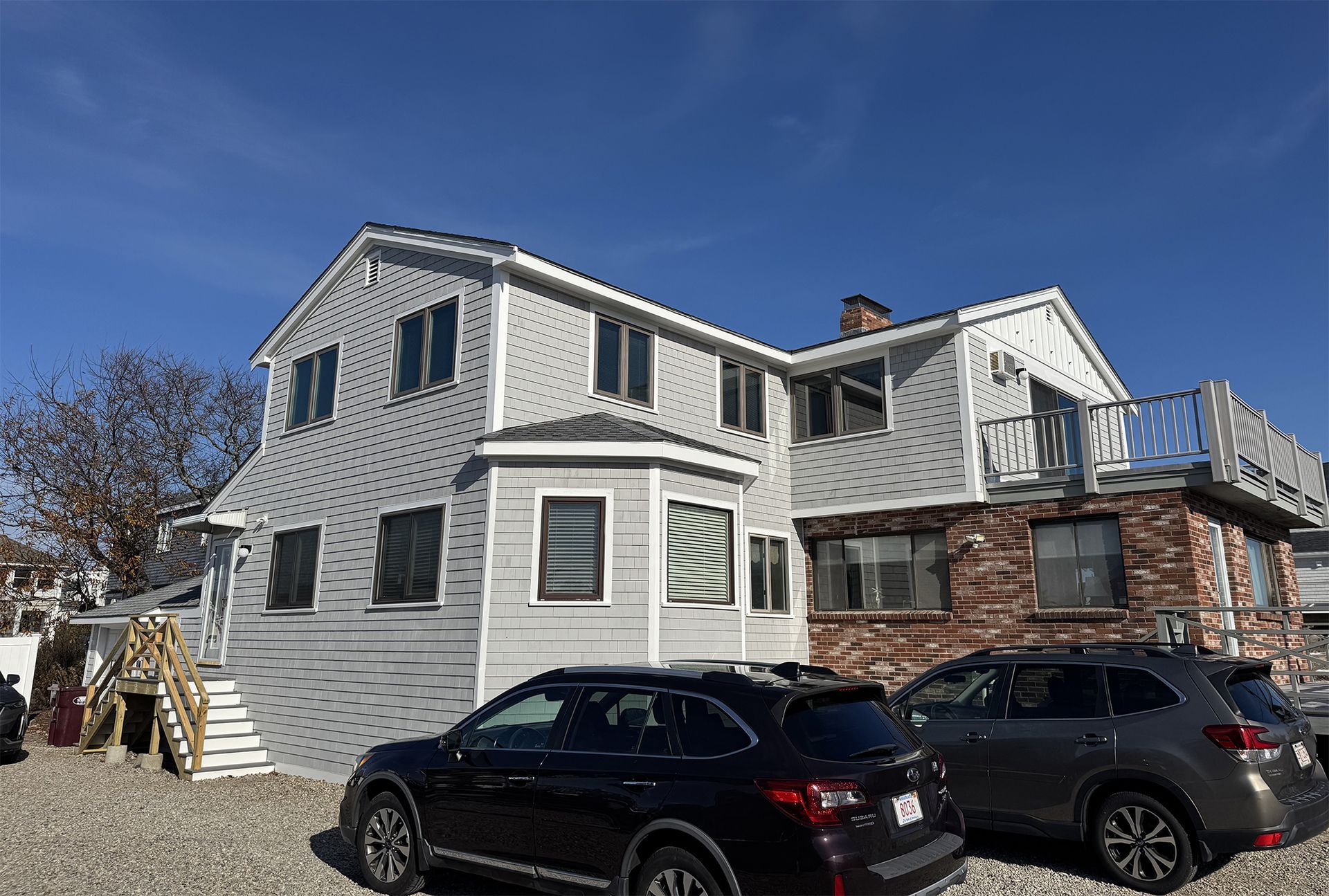 Two cars are parked in front of a large house.