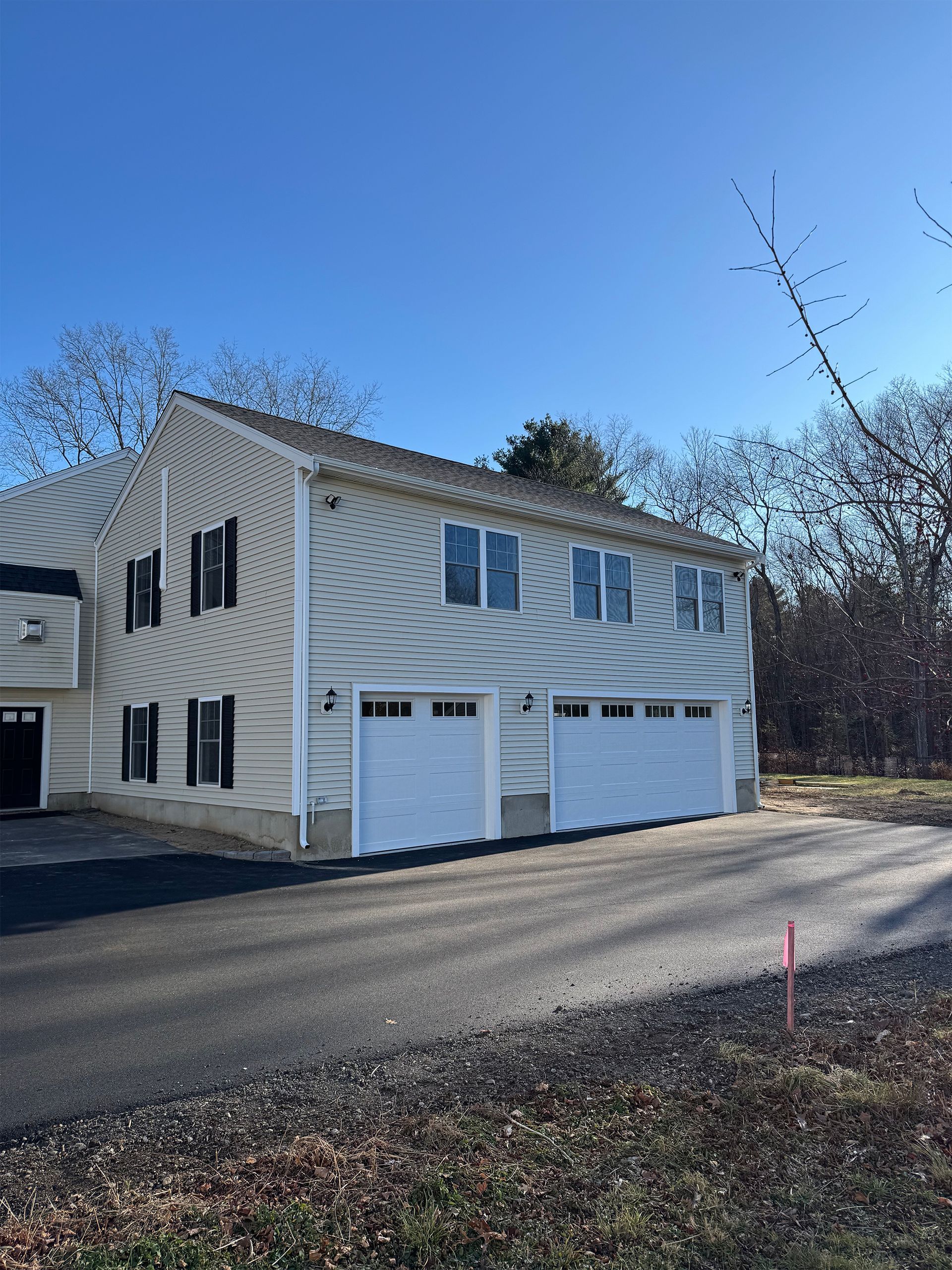 A white house with two garage doors and a driveway