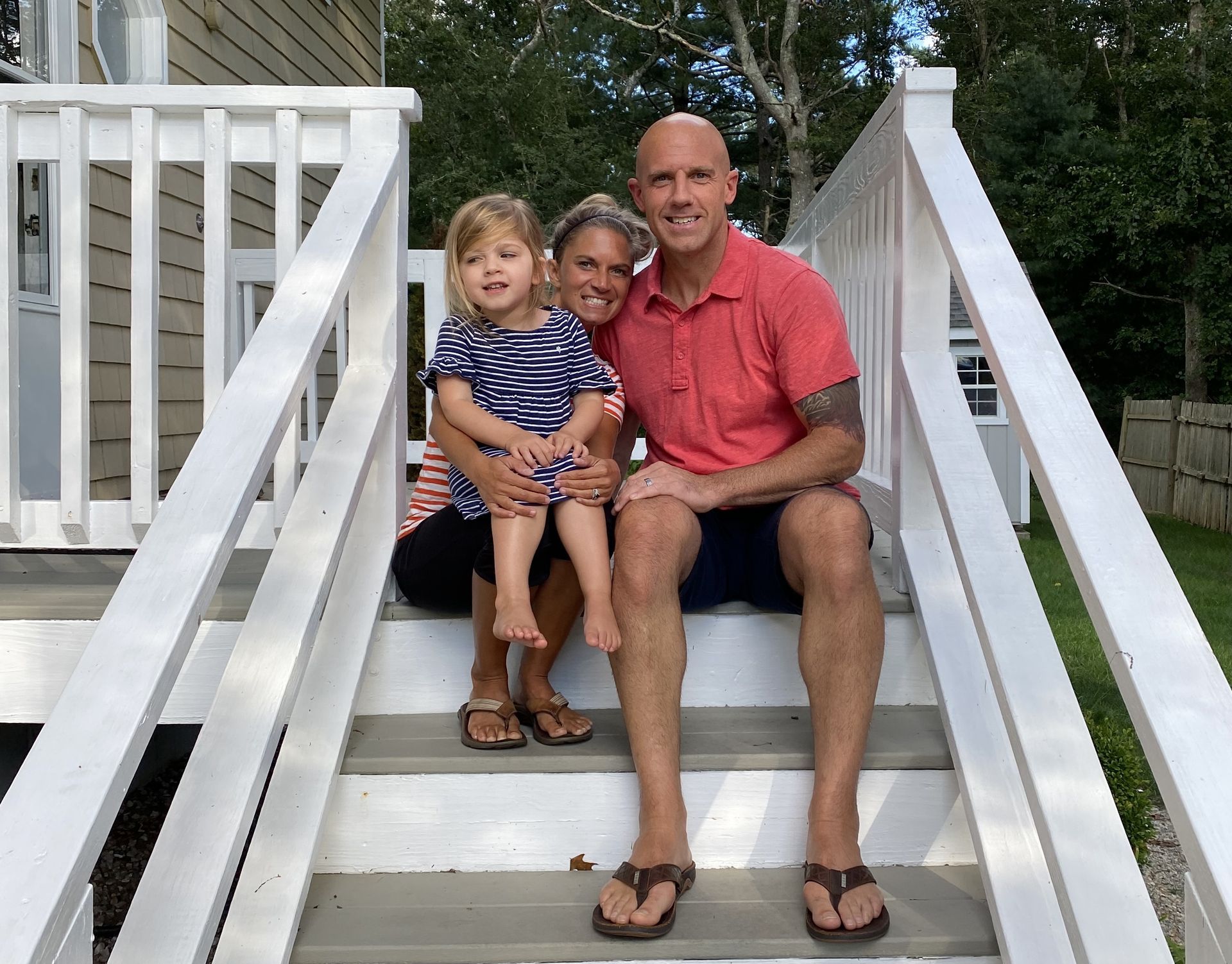 A family is sitting on the steps of a house.