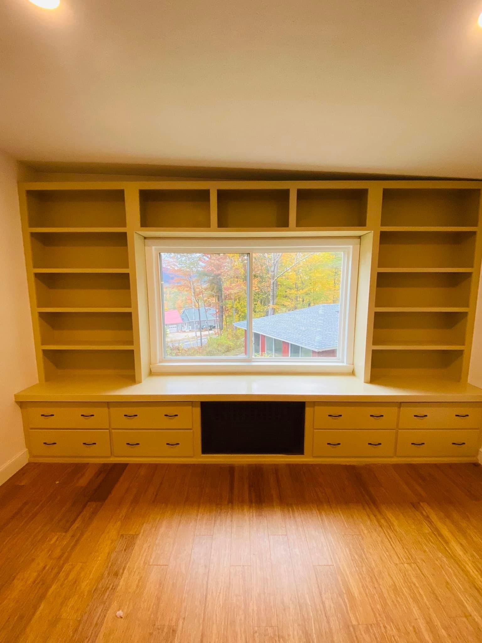 a room with a window and lots of shelves and drawers