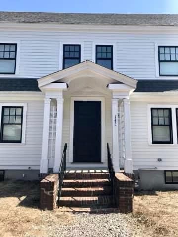 a white house with a black door and stairs in front of it