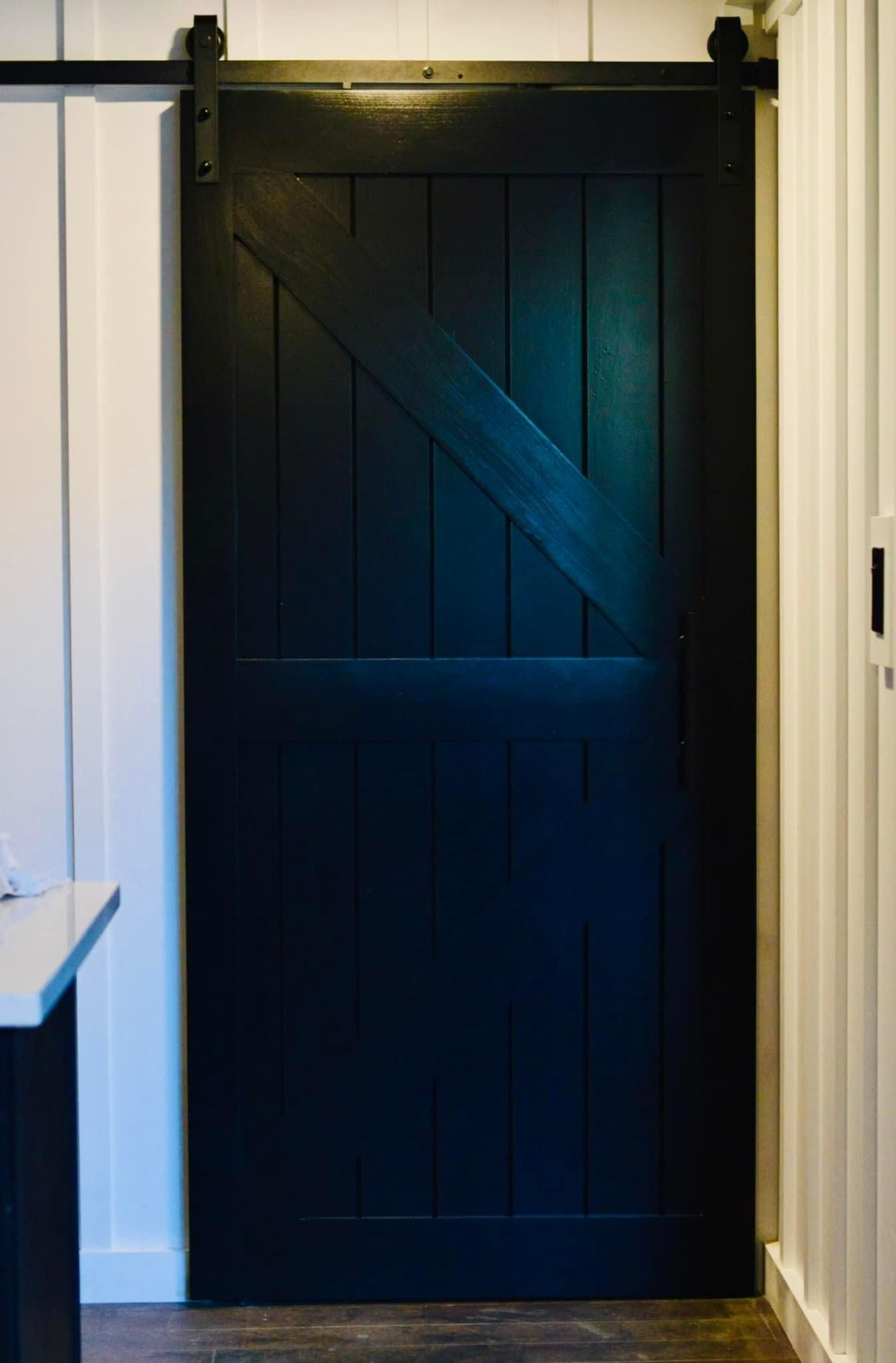 a black sliding barn door is hanging on a white wall in a hallway