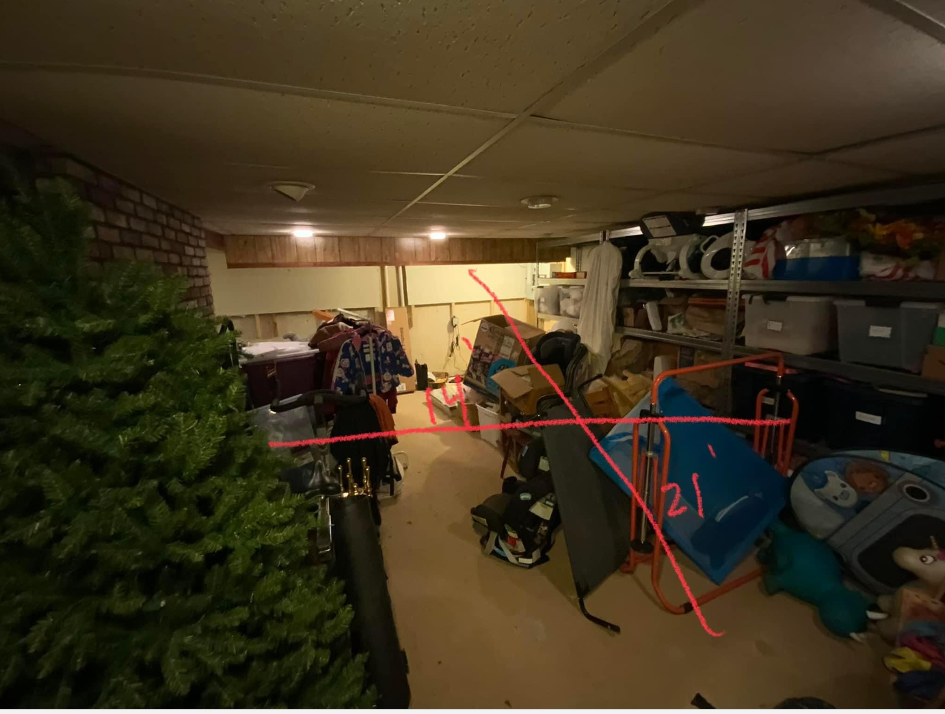 a very cluttered basement with a Christmas tree on the side