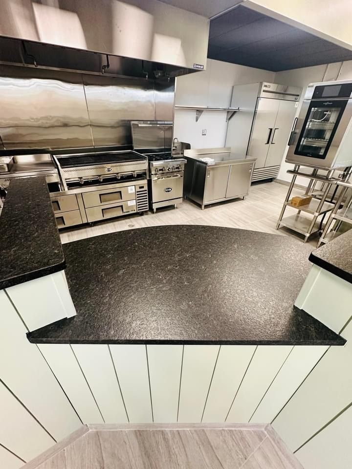 A kitchen with a black counter top and stainless steel appliances