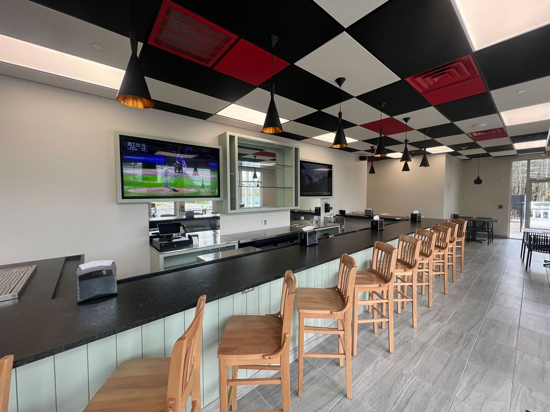 A long bar with stools and a television on the wall