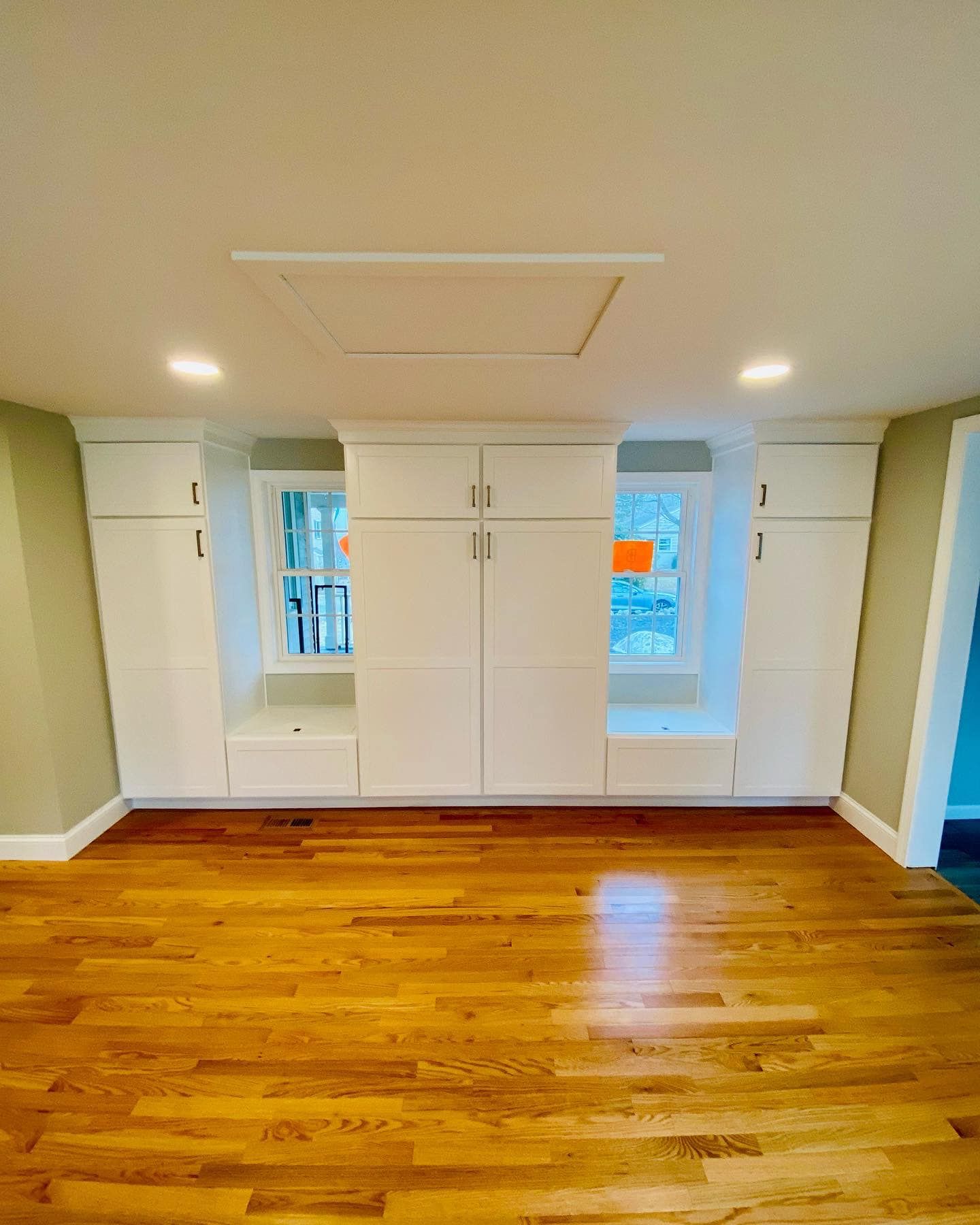 an empty room with hardwood floors and white cabinets