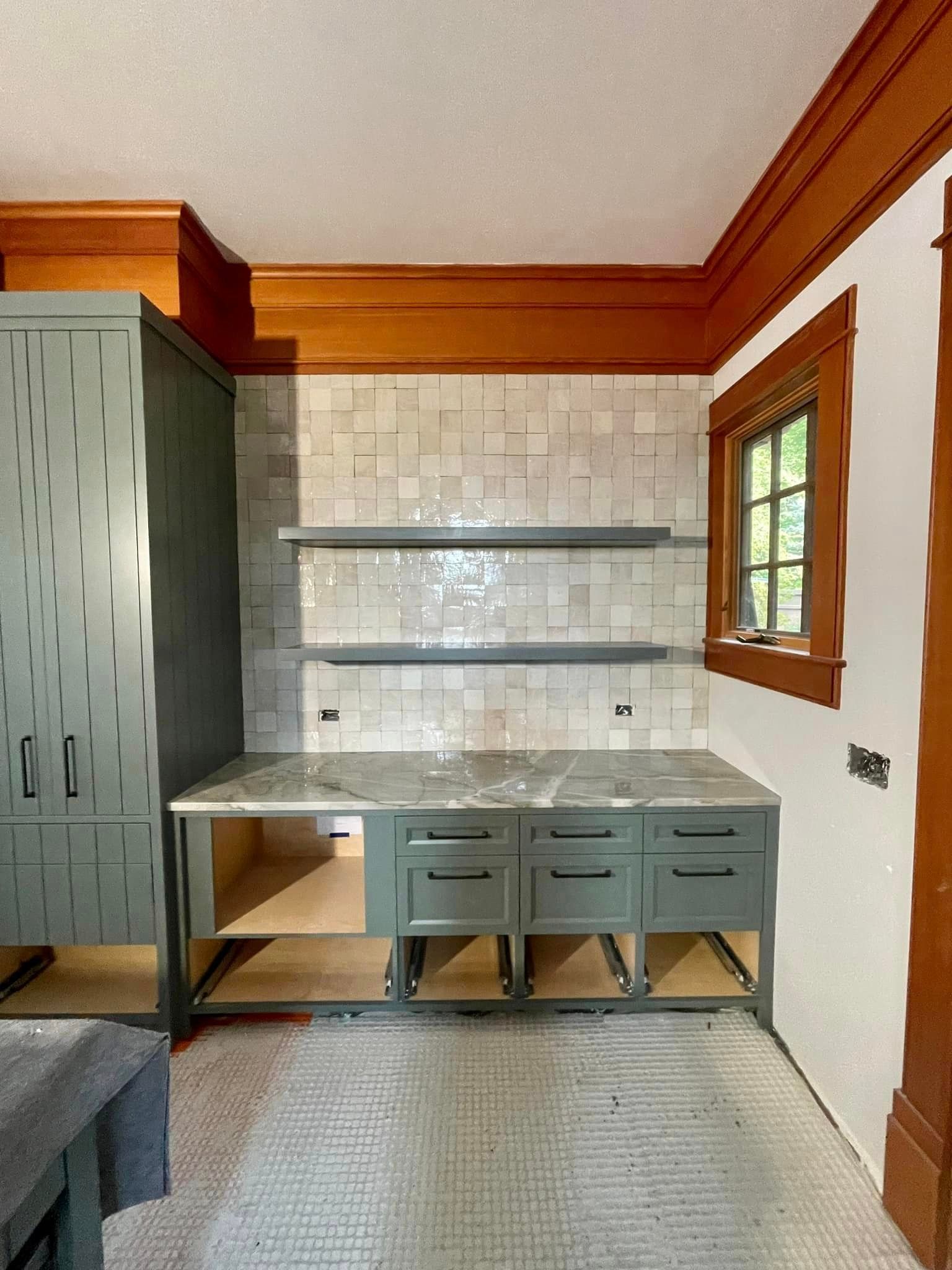 a kitchen with green cabinets and a marble counter top