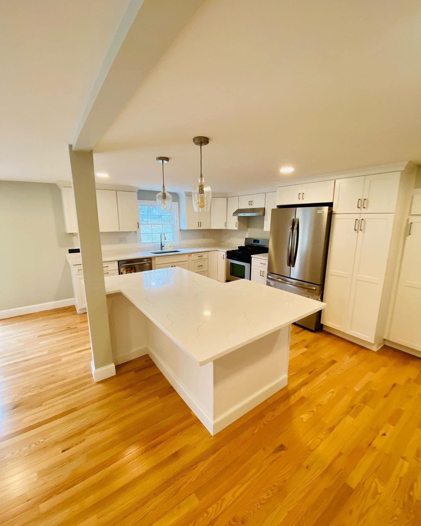 a kitchen with white cabinets, stainless steel appliances, hardwood floors and a large island