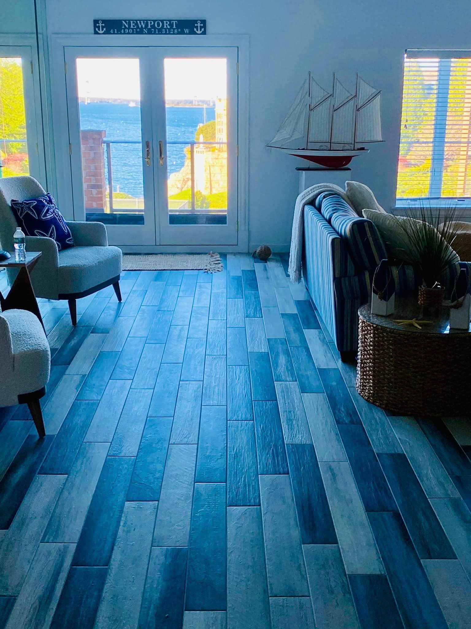 a living room with a blue and white wooden floor and a sailboat on the wall