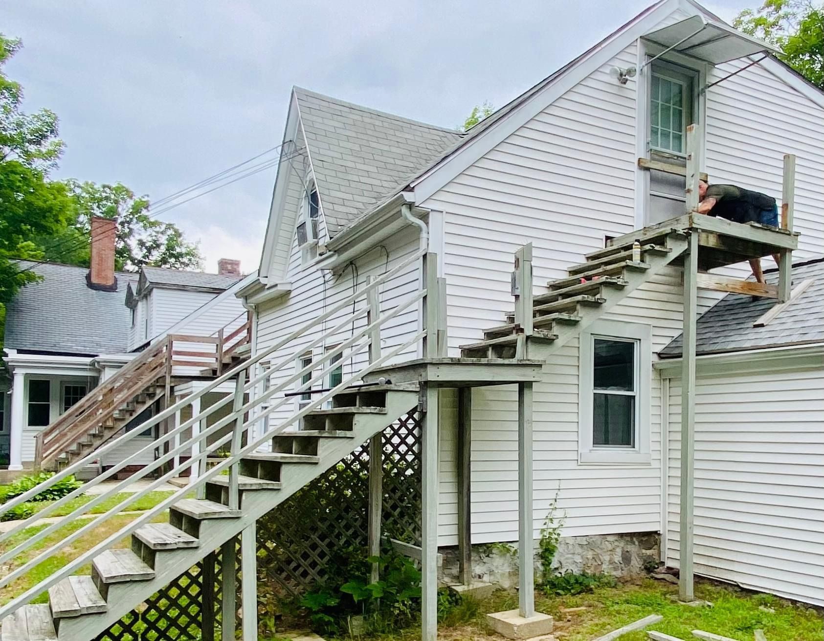 a white house with stairs leading up to the second floor