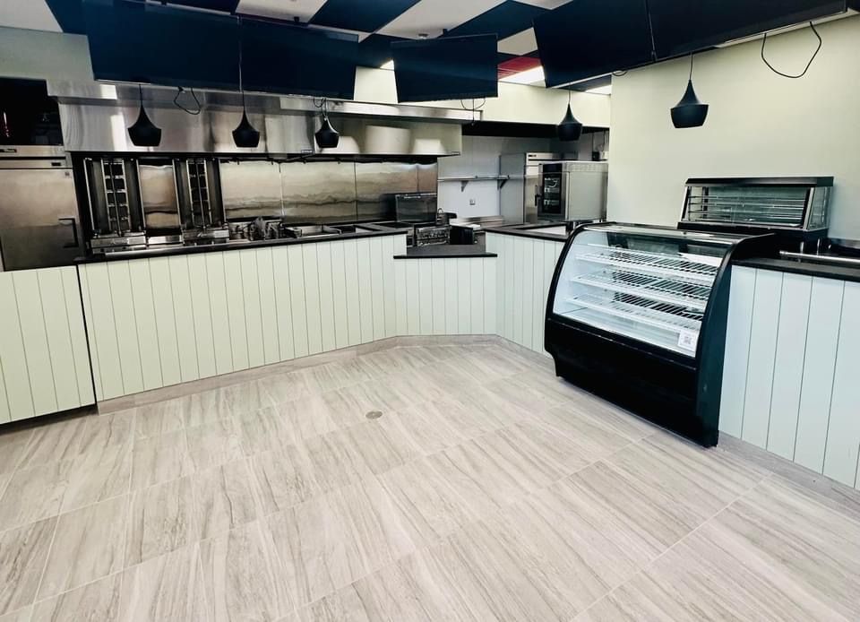 A large empty kitchen with stainless steel appliances and a display case.