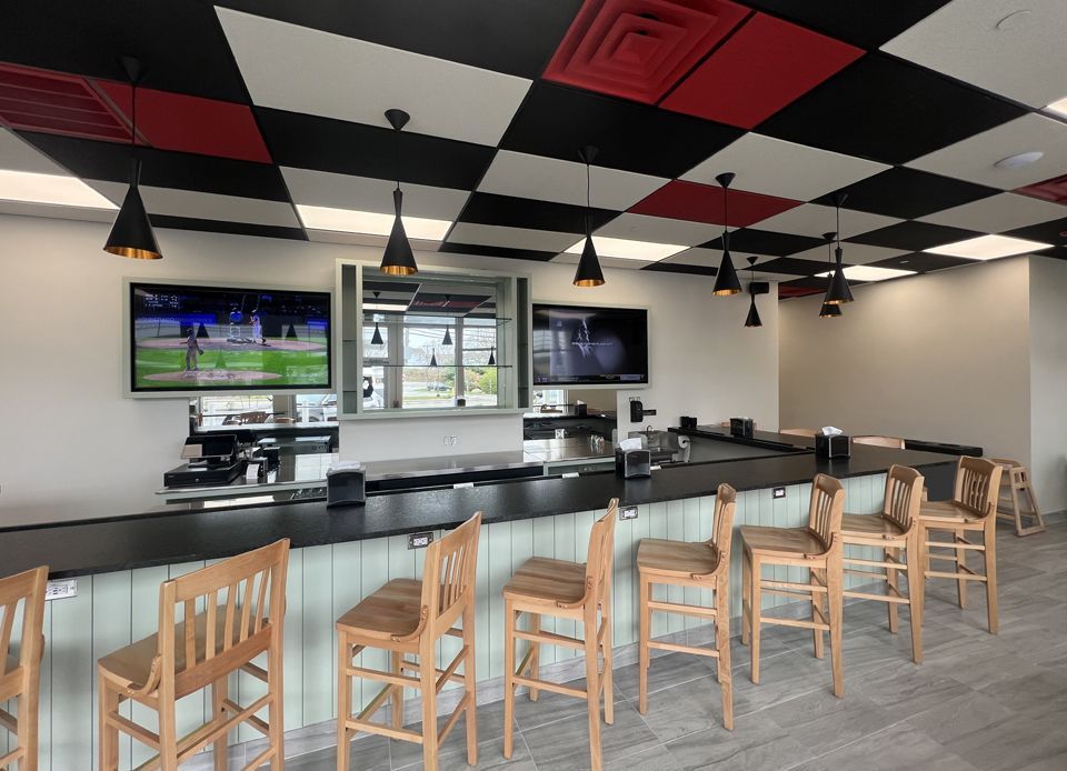 A restaurant with a long bar and chairs and a checkered ceiling.