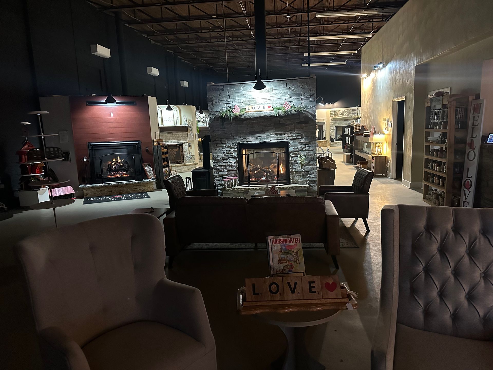 A living room with a fireplace, couch, chairs, and a table with a love sign on it.