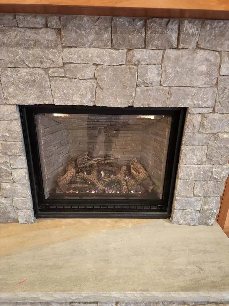 A man is standing in front of a fireplace with a glass door.