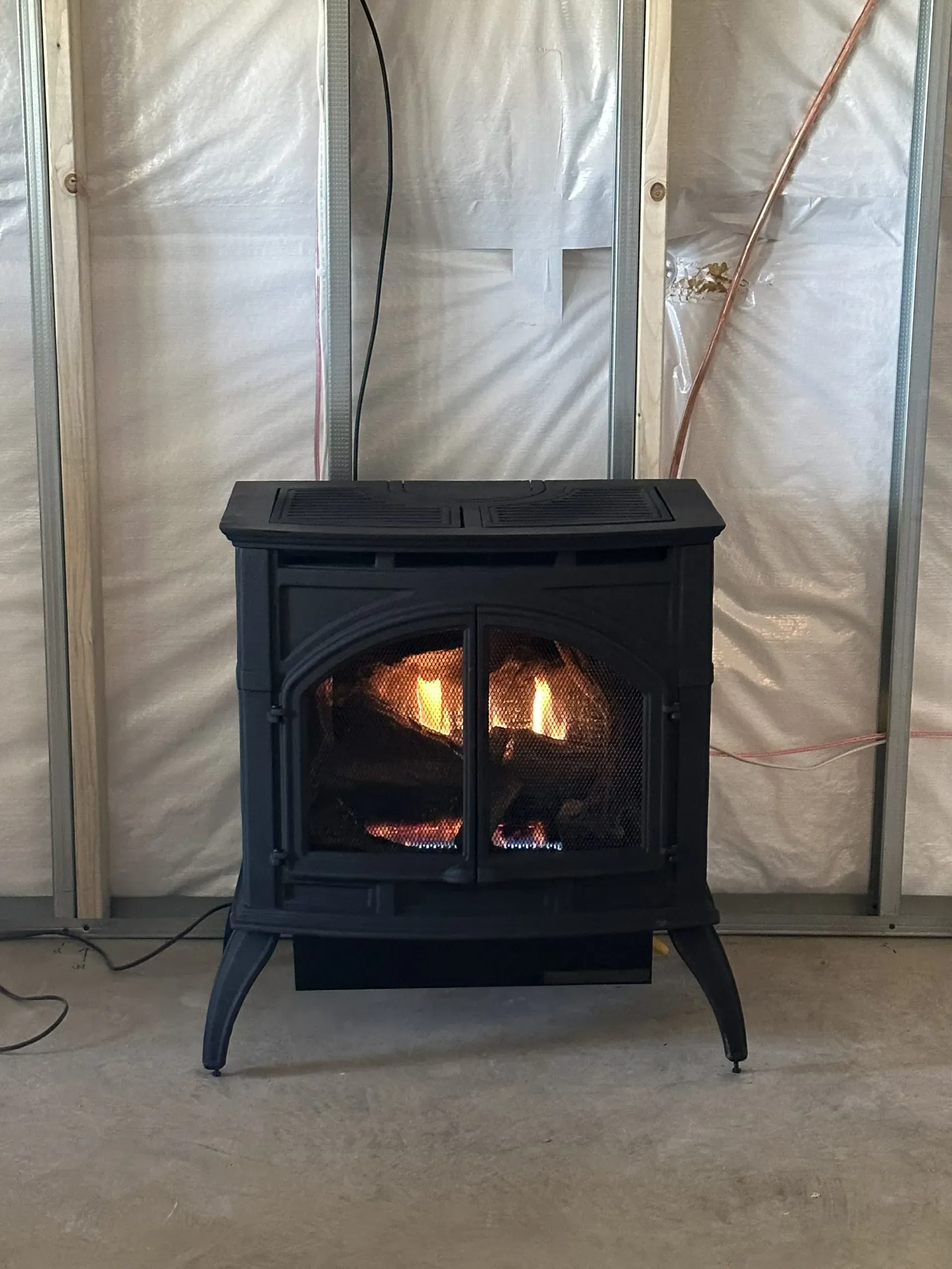 A wood stove is sitting in a room next to a wall.