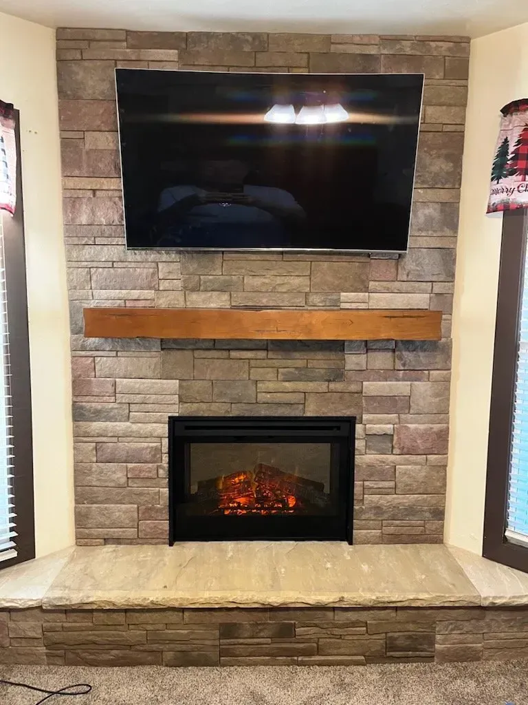 A fireplace with a flat screen tv mounted above it.
