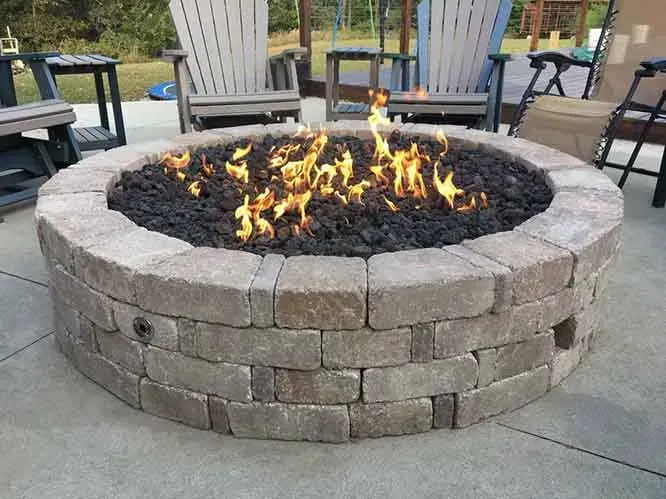 A fire pit is surrounded by chairs on a patio.