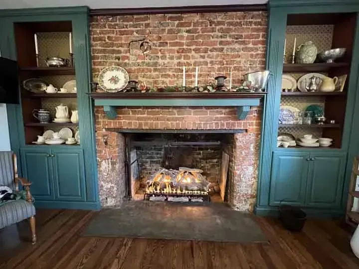 A living room with a brick fireplace and blue cabinets.
