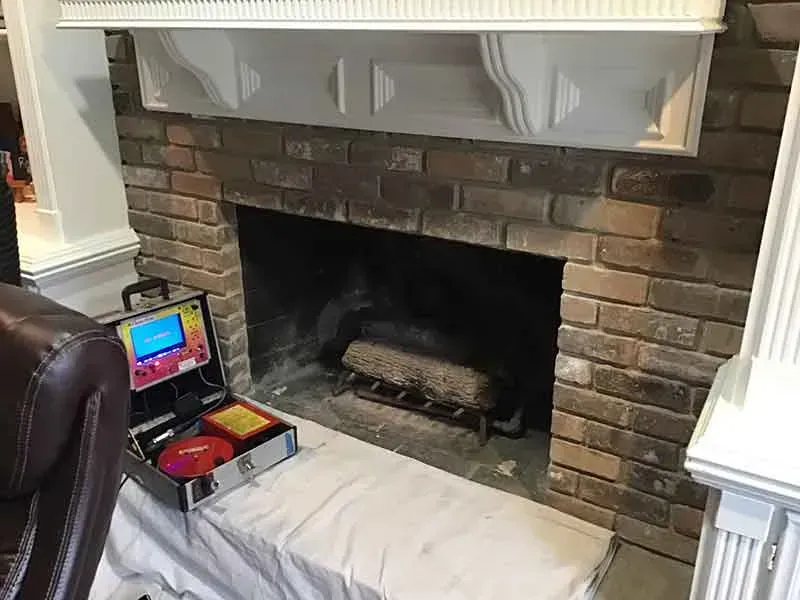 A fireplace in a living room with a toolbox in front of it.