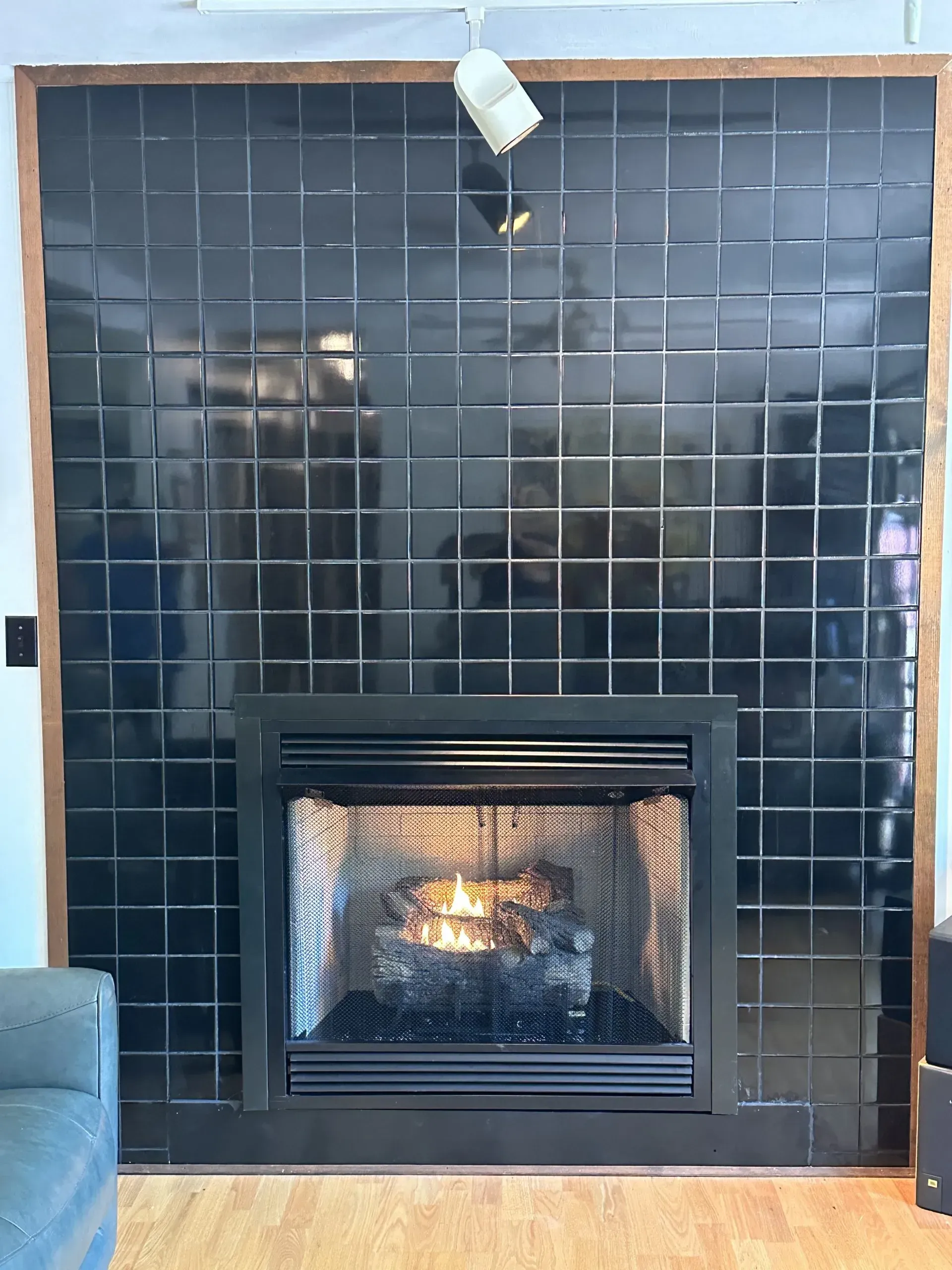 A fireplace in a living room with black tiles on the wall.